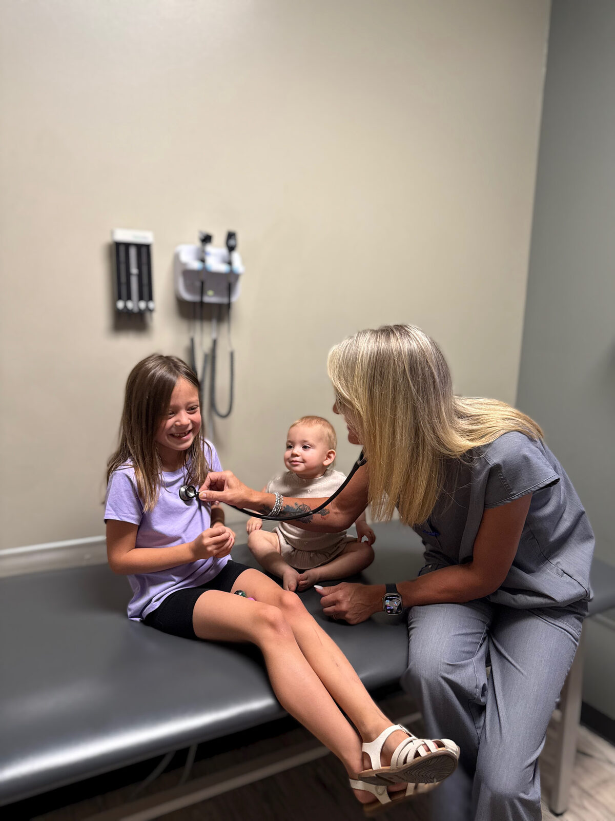 Provider examining two young patients in an exam room